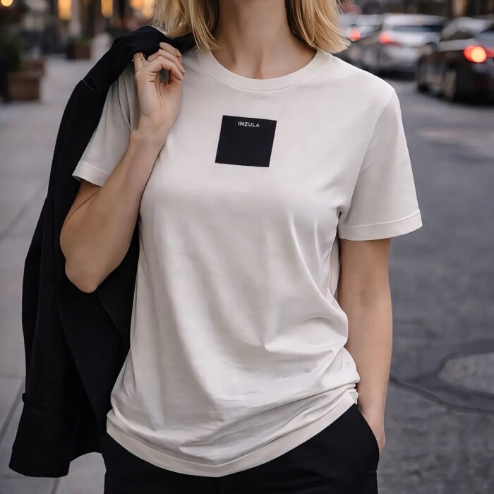 INZULA Vintage White t-shirt with black square logo placed on COSMOS, LIFE, and SCRIPTURE books in a minimalist luxury setting